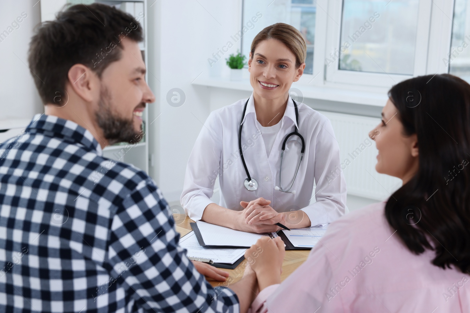 Photo of Couple having appointment with fertility doctor in clinic. Patient consultation