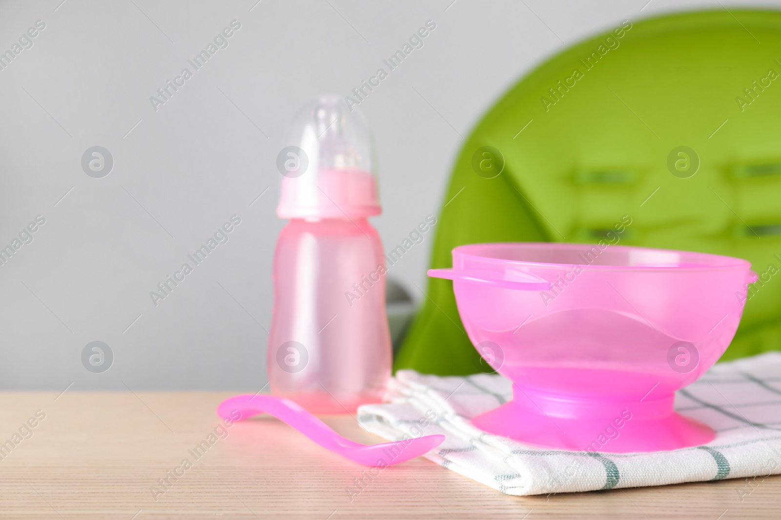 Photo of Set of plastic dishware on wooden table. Serving baby food