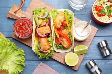 Photo of Delicious fish tacos served on blue wooden table, flat lay