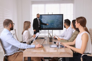 Business trainer using interactive board in meeting room during presentation