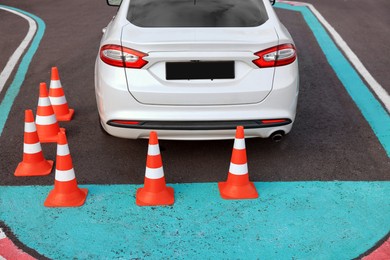 Photo of Modern car on driving school test track with traffic cones, above view