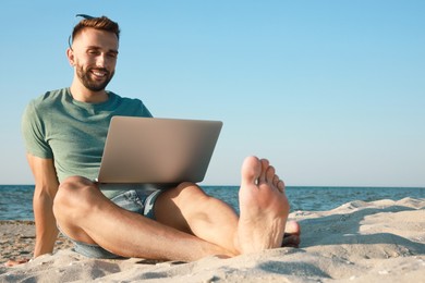 Photo of Man working with modern laptop on beach