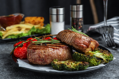 Delicious beef medallions served on grey table, closeup