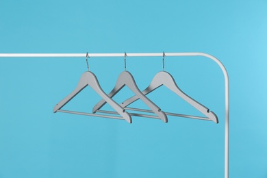 Metal rack with clothes hangers on color background