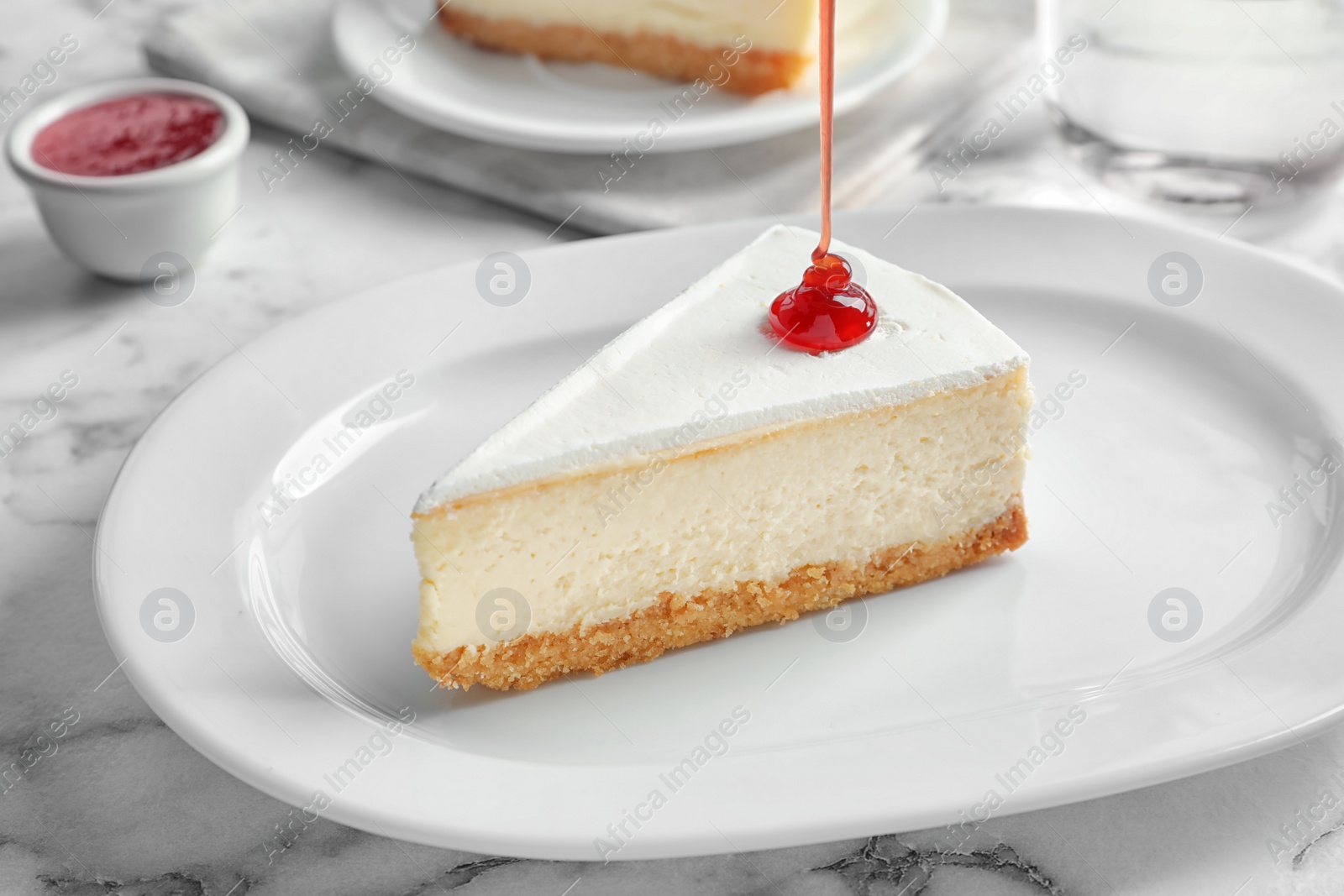 Photo of Pouring sweet jam onto delicious cheesecake served on plate