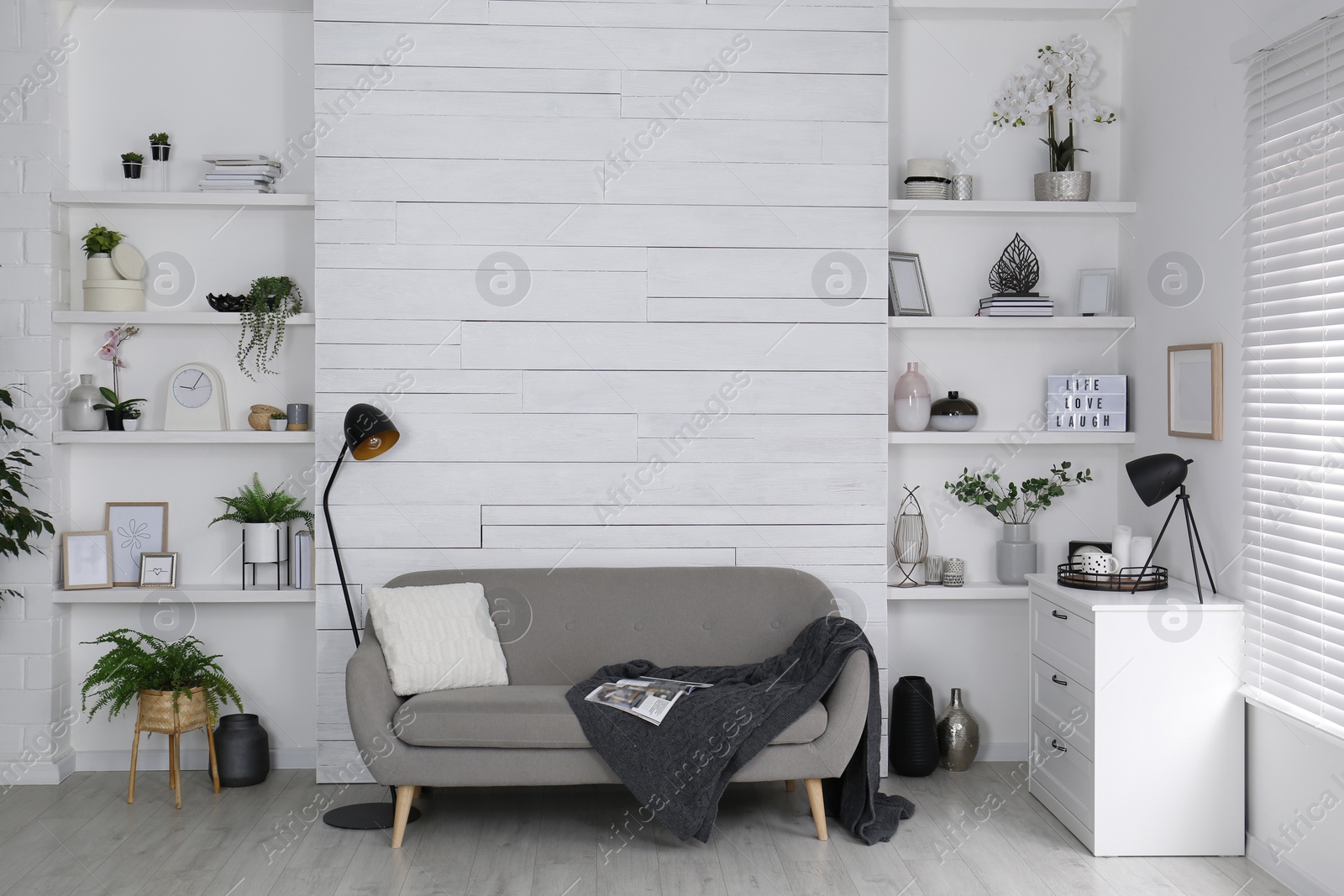 Photo of Stylish living room interior with comfortable sofa, wall shelves and beautiful decor elements