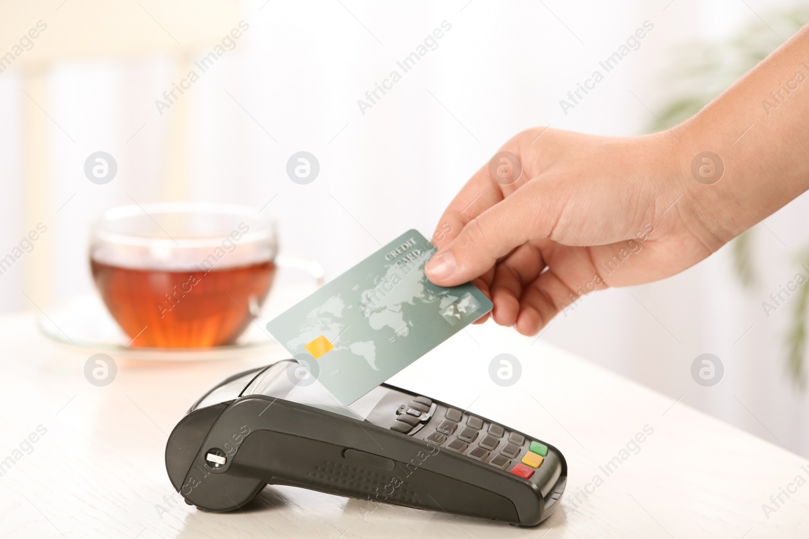 Photo of Woman using terminal for contactless payment with credit card in cafe