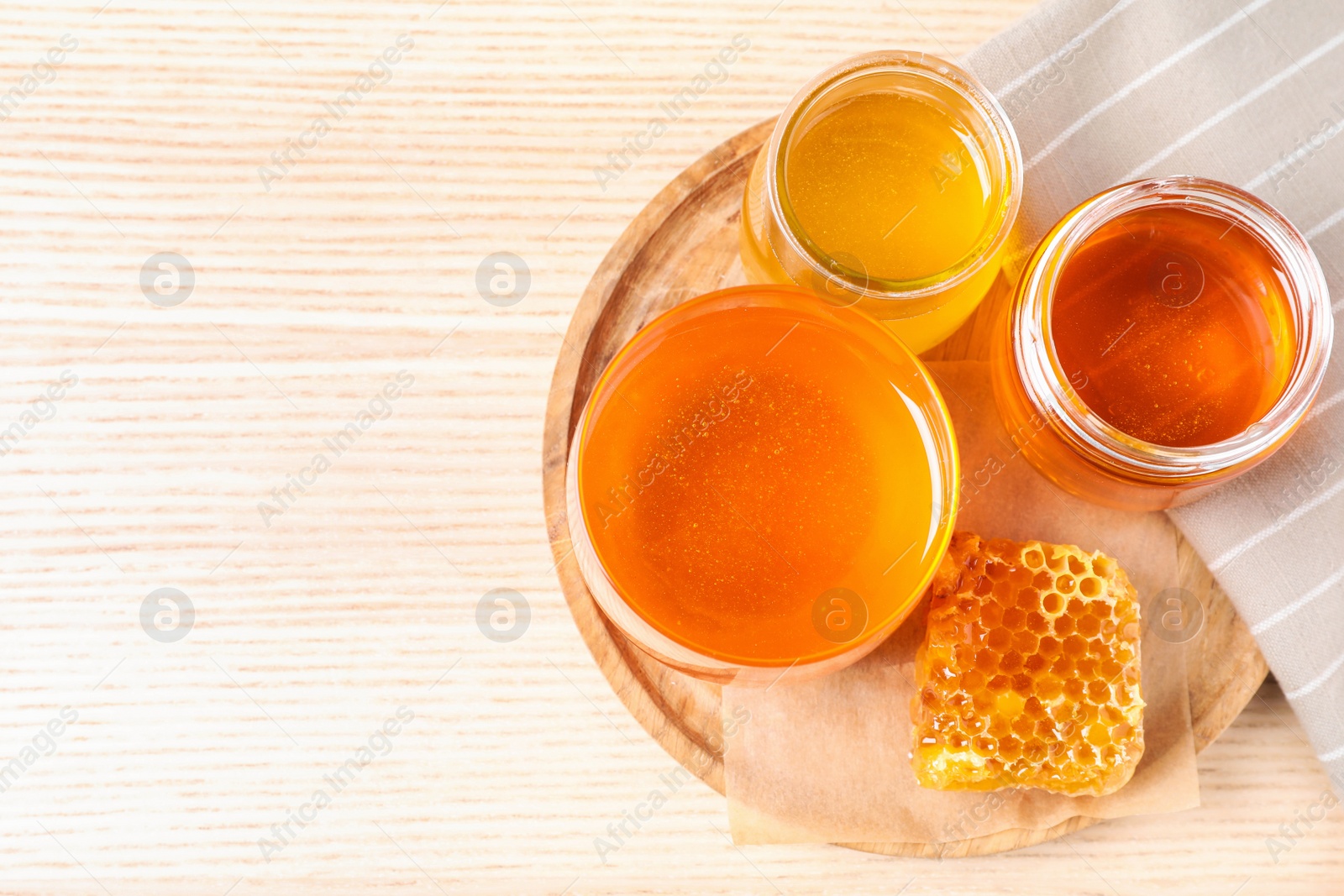 Photo of Tasty honey on white wooden table, top view. Space for text