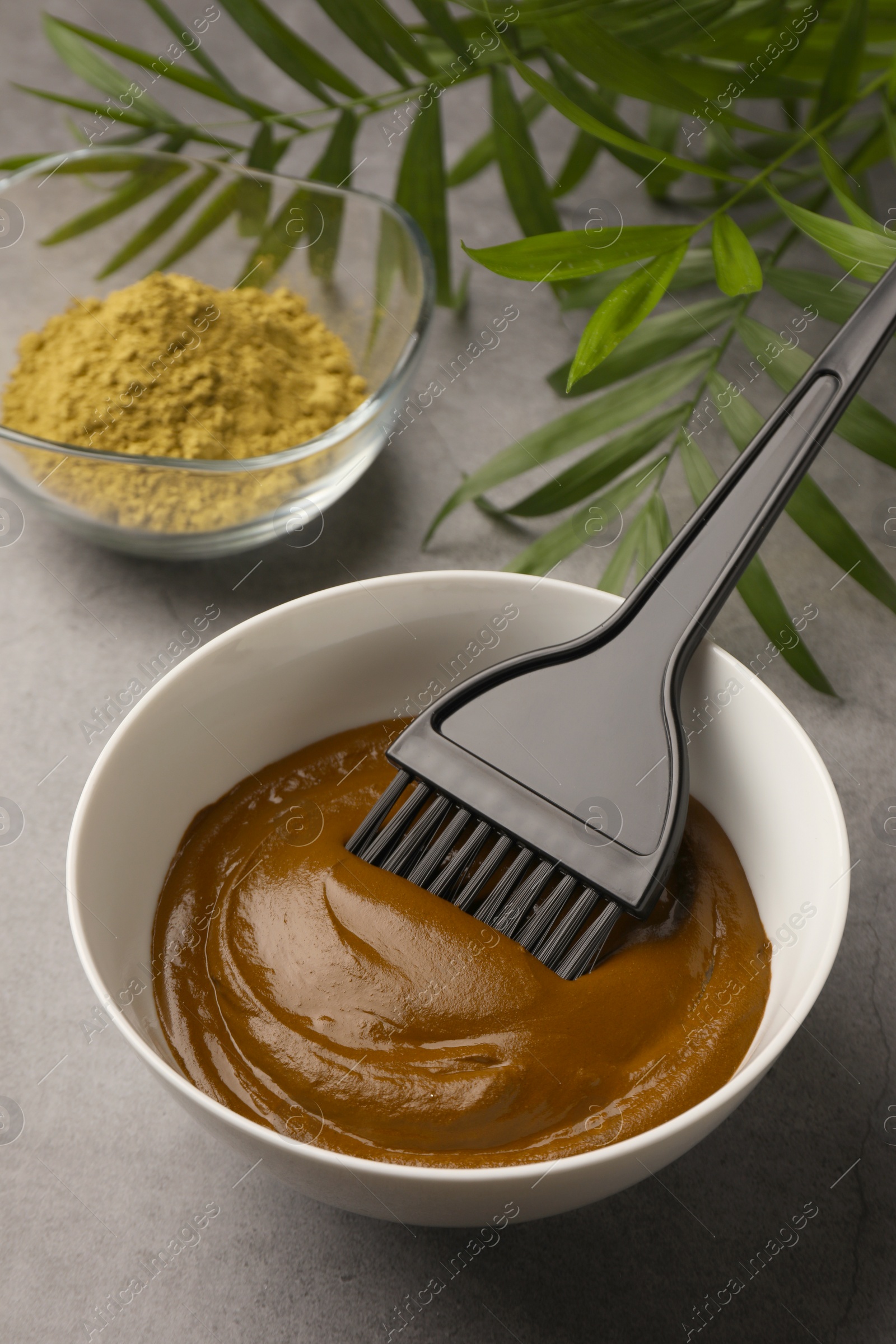 Photo of Henna cream with brush and powder on light grey table. Natural hair coloring