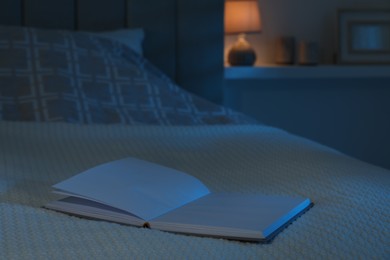 Open book on large bed at night