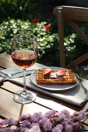 Delicious Belgian waffle with fresh strawberries and wine served on table in spring garden