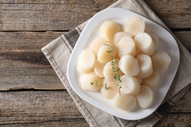 Photo of Fresh raw scallops and thyme on wooden table, top view. Space for text