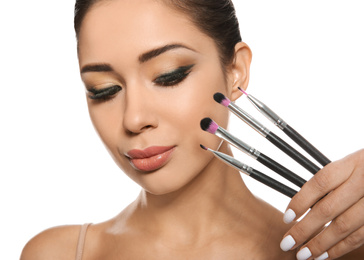 Beautiful woman with makeup brushes on white background