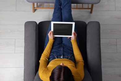 Woman working with tablet in armchair, top view