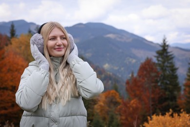 Young beautiful woman wearing warm earmuffs in mountains