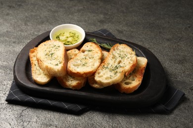 Tasty baguette with garlic and dill served on grey textured table