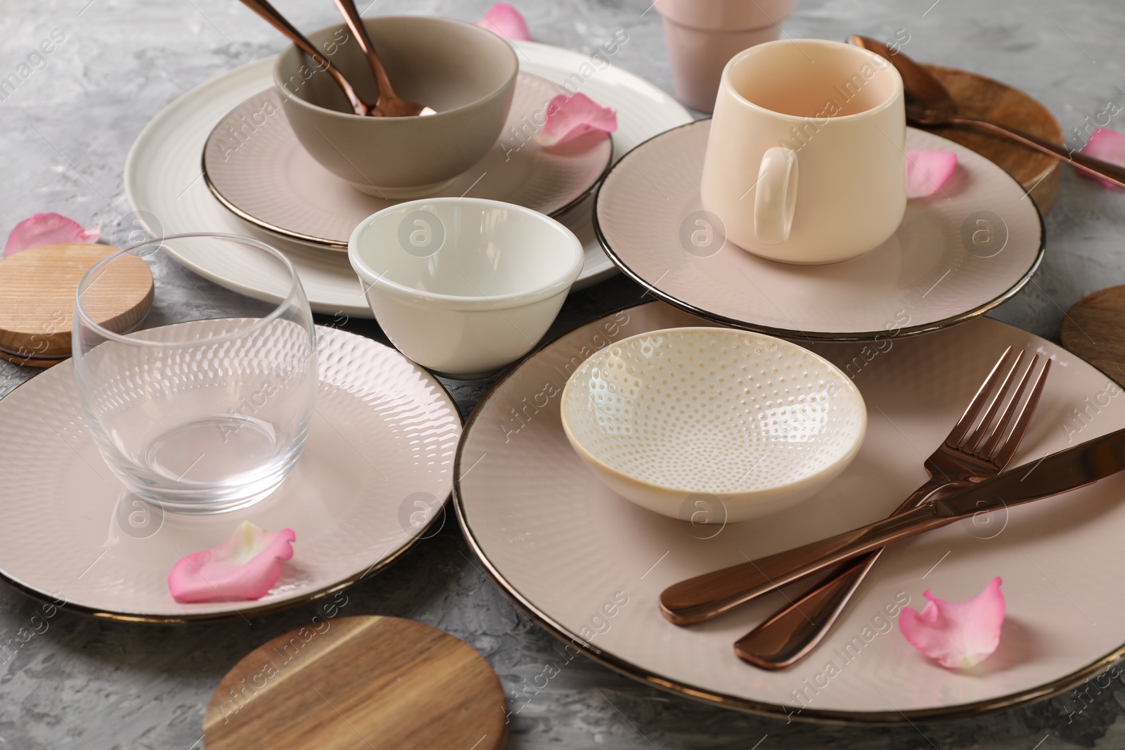 Photo of Stylish table setting. Dishes, cutlery, cup and petals