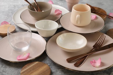 Photo of Stylish table setting. Dishes, cutlery, cup and petals