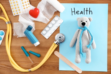 Photo of Flat lay composition with toy bear and medical items on wooden background. Children's doctor