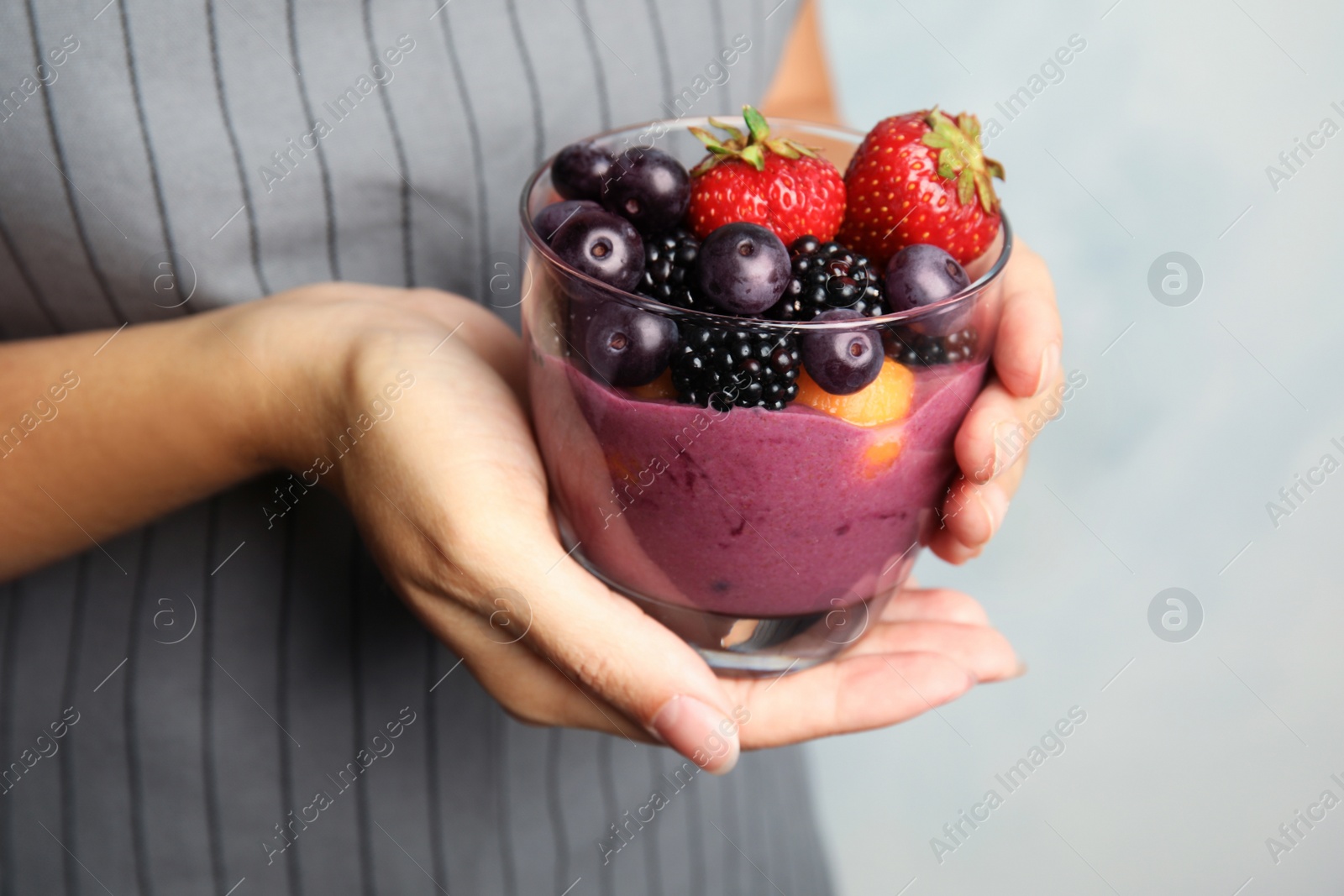 Photo of Woman holding glass with tasty acai smoothie, closeup