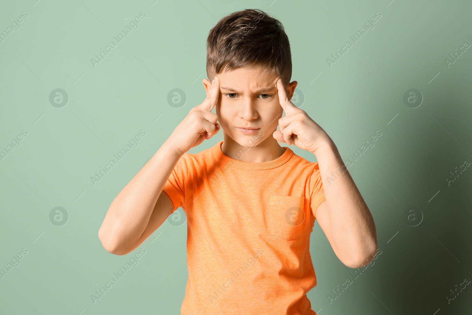 Photo of Little boy suffering from headache on color background