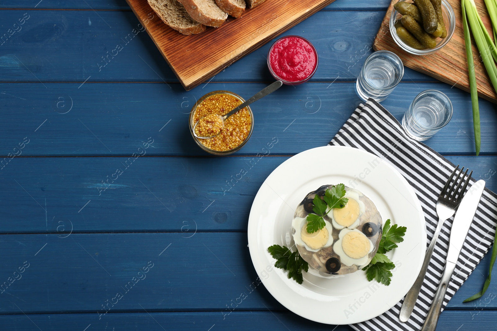 Photo of Delicious aspic with meat served on blue wooden table, flat lay. Space for text