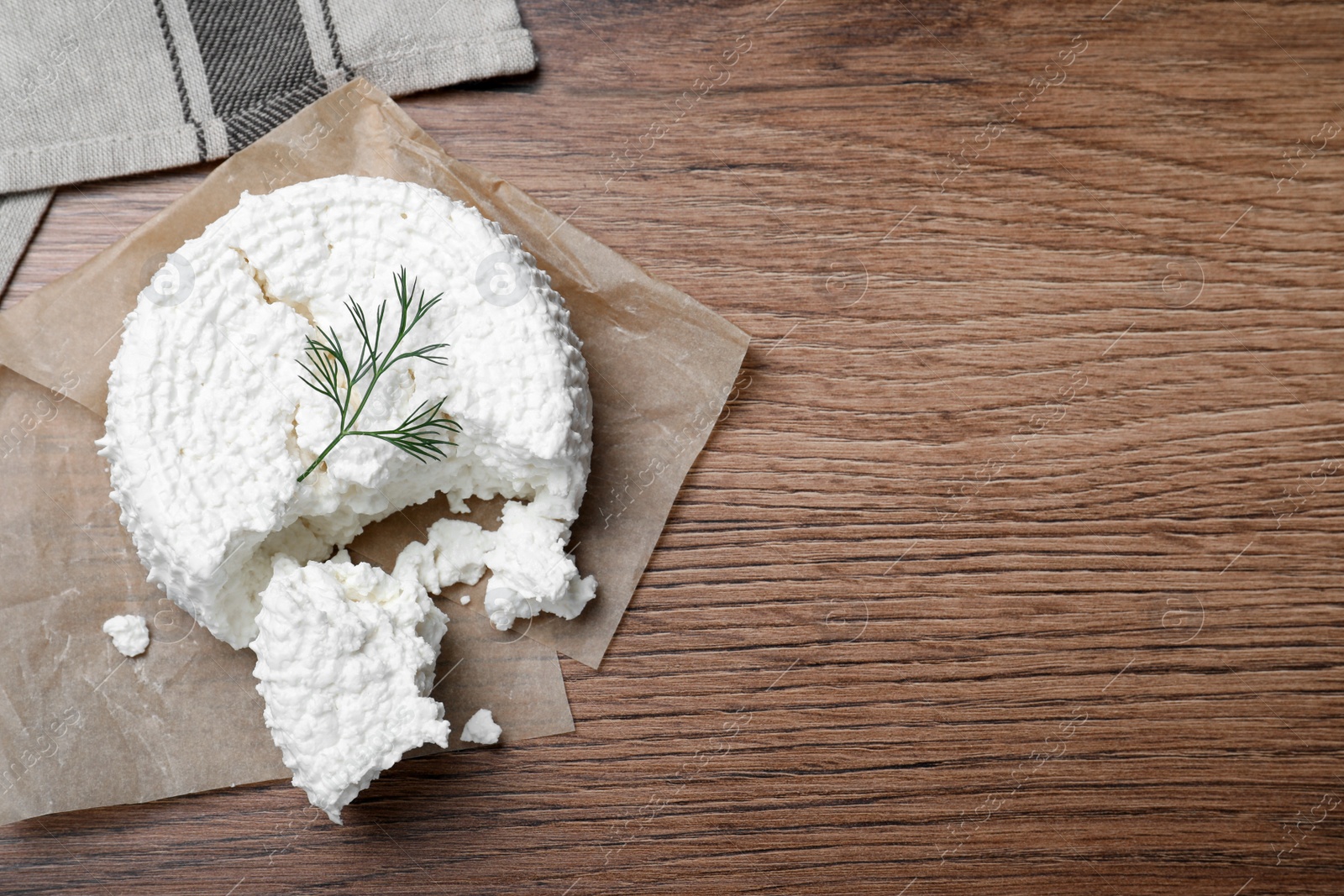 Photo of Delicious cottage cheese with dill on wooden table, top view. Space for text