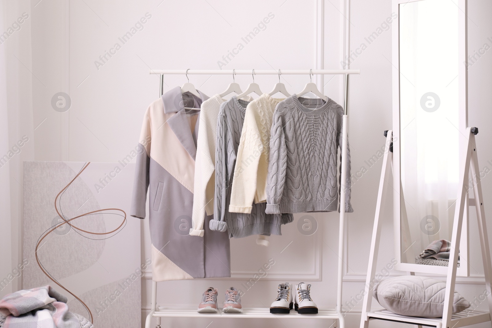 Photo of Rack with stylish warm clothes and mirror in dressing room