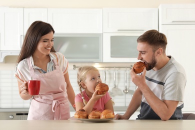 Photo of Happy family eating freshly oven baked buns in kitchen