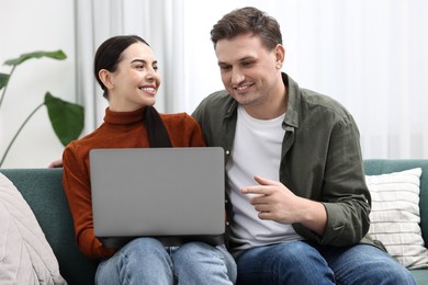 Photo of Happy couple using laptop together at home