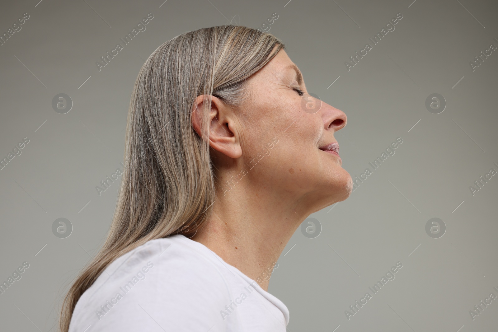 Photo of Beautiful woman with healthy skin on grey background, low angle view