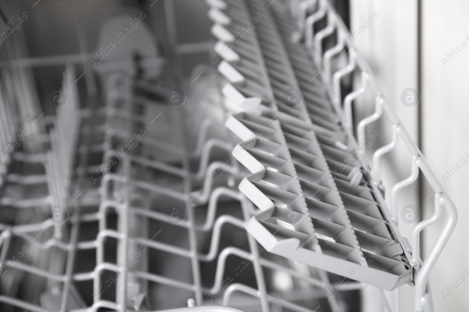 Photo of Open clean empty dishwasher in kitchen, closeup