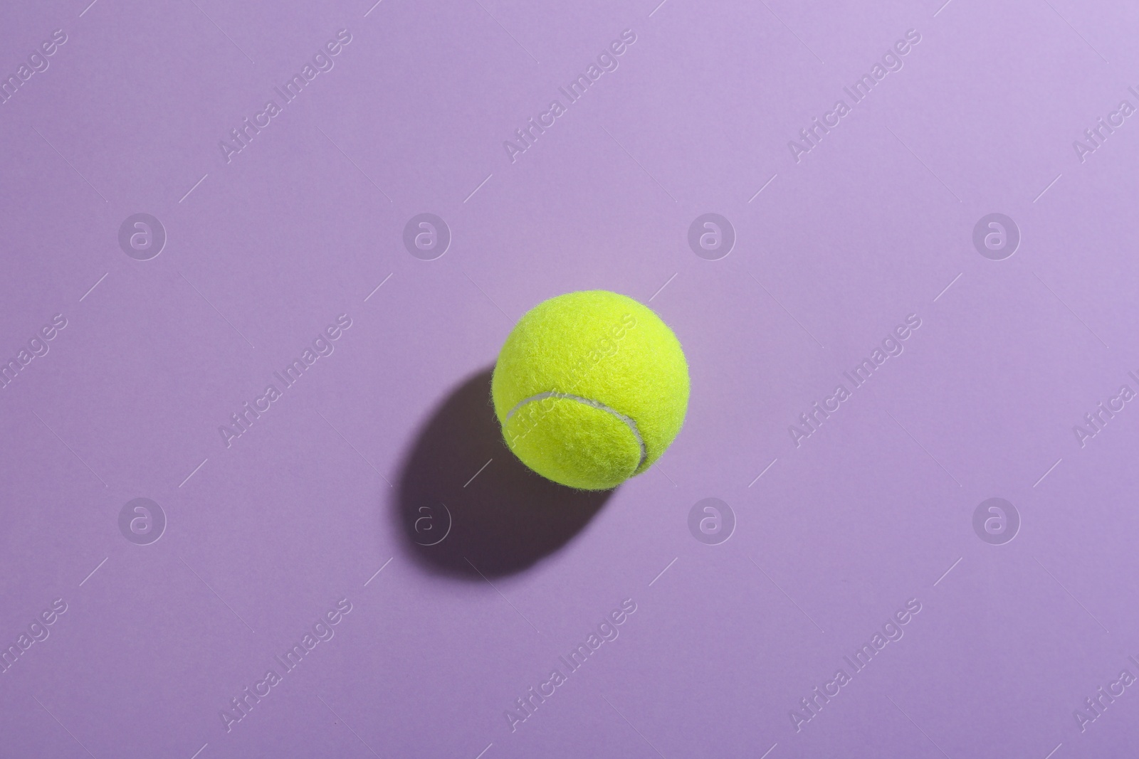 Photo of Tennis ball on violet background, top view. Sports equipment