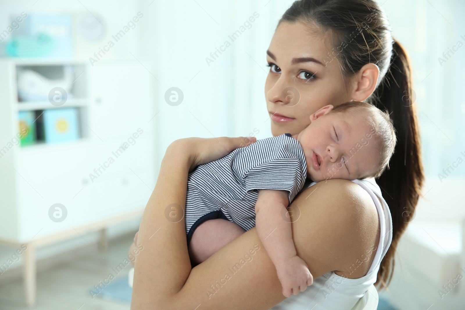 Photo of Young woman with her newborn baby at home. Space for text