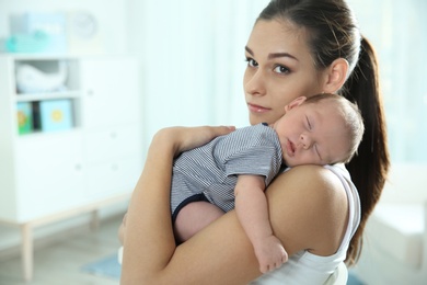 Young woman with her newborn baby at home. Space for text