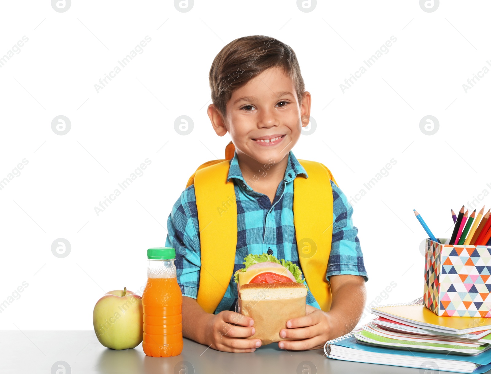 Photo of Schoolboy with healthy food and backpack sitting at table on white background