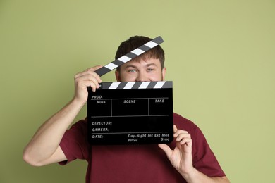 Photo of Making movie. Man with clapperboard on green background