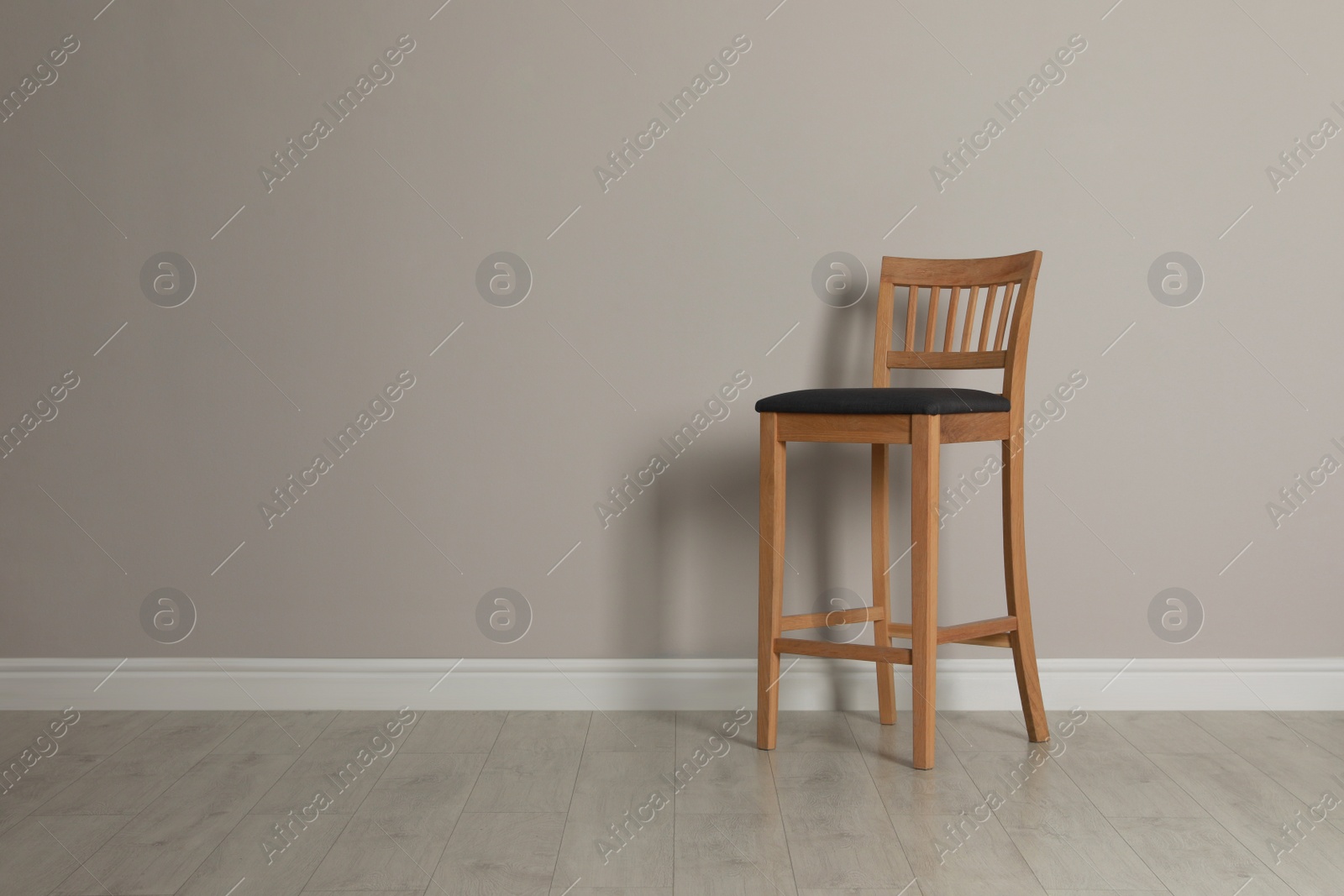 Photo of Stylish bar stool near light grey wall indoors. Space for text