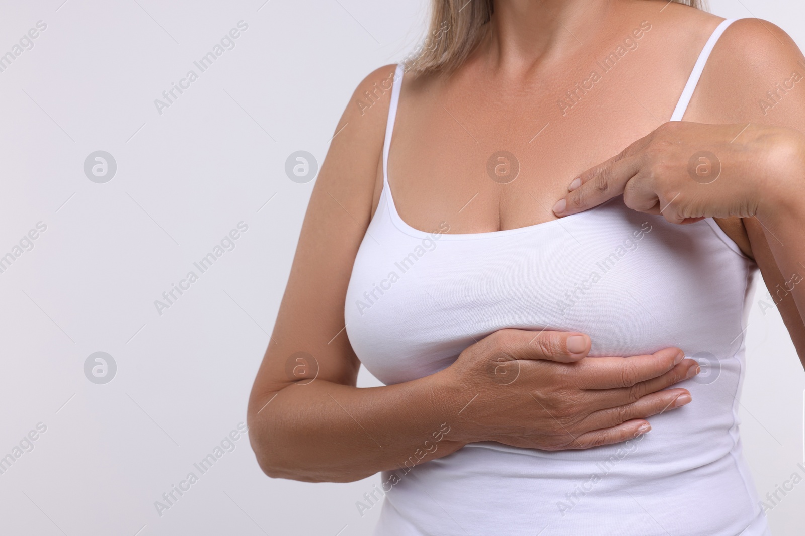 Photo of Woman doing breast self-examination on white background, closeup. Space for text