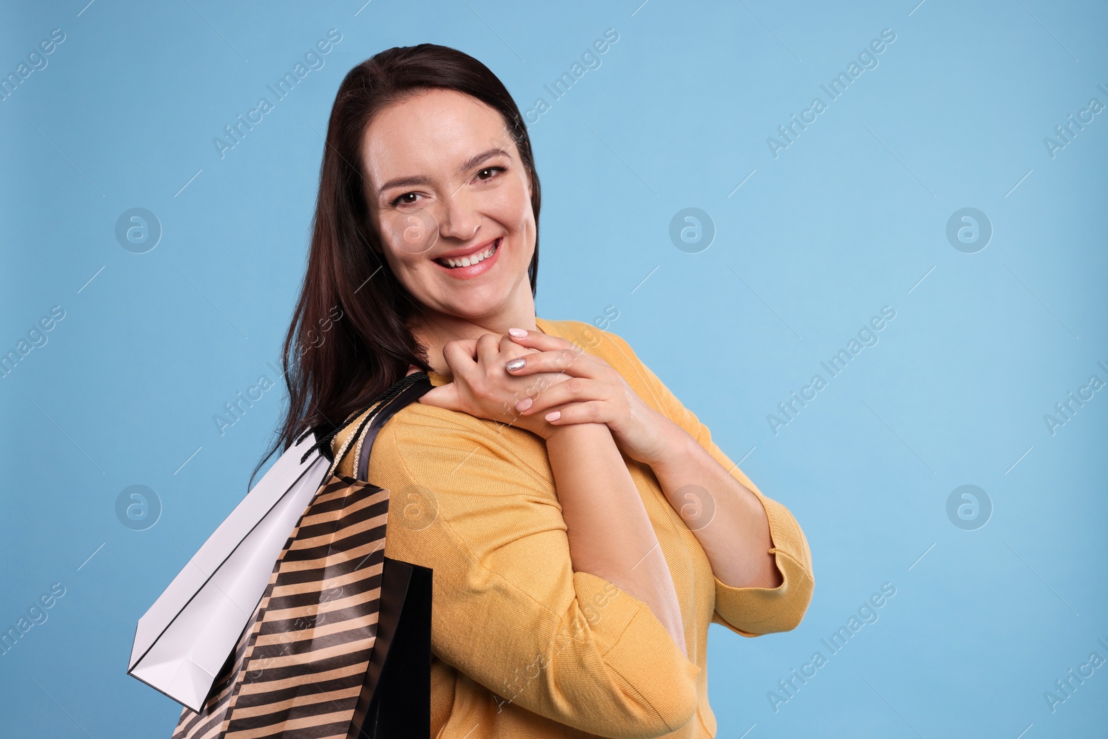 Photo of Beautiful overweight woman with shopping bags on turquoise background