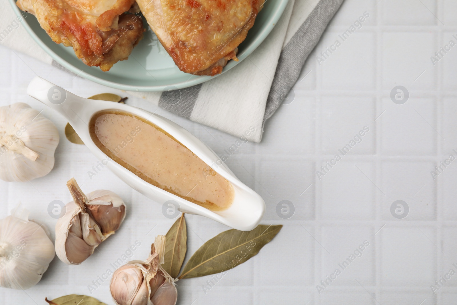 Photo of Flat lay composition with delicious turkey gravy in sauce boat on white tiled table. Space for text