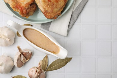 Flat lay composition with delicious turkey gravy in sauce boat on white tiled table. Space for text