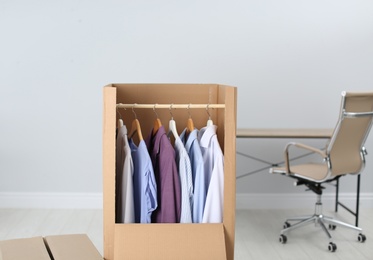 Photo of Wardrobe box with clothes on hangers indoors