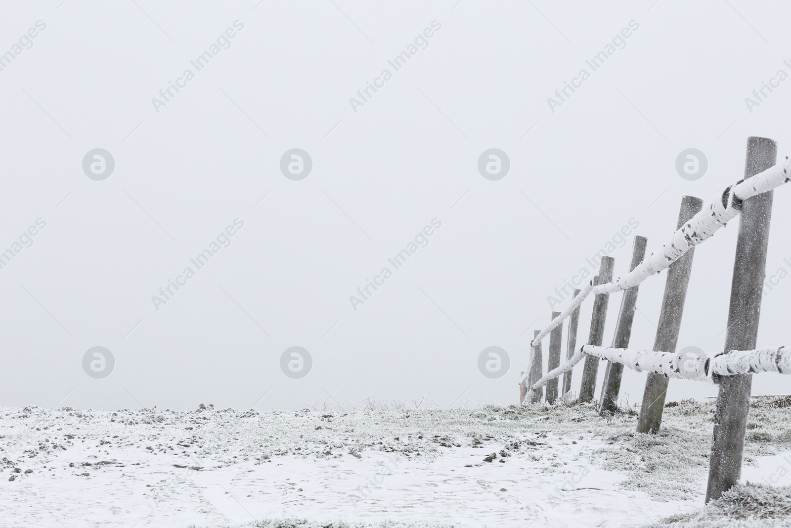 Photo of View of wooden fence covered with snow outdoors on winter day