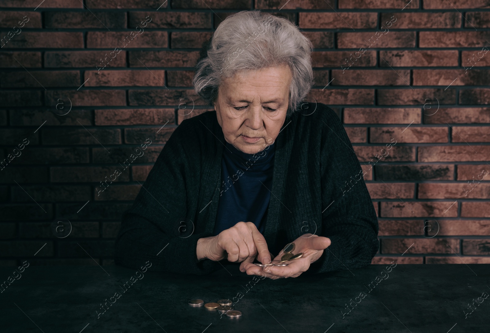 Photo of Poor mature woman counting coins at table