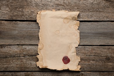 Photo of Sheet of old parchment paper with wax stamp on wooden table, top view. Space for design