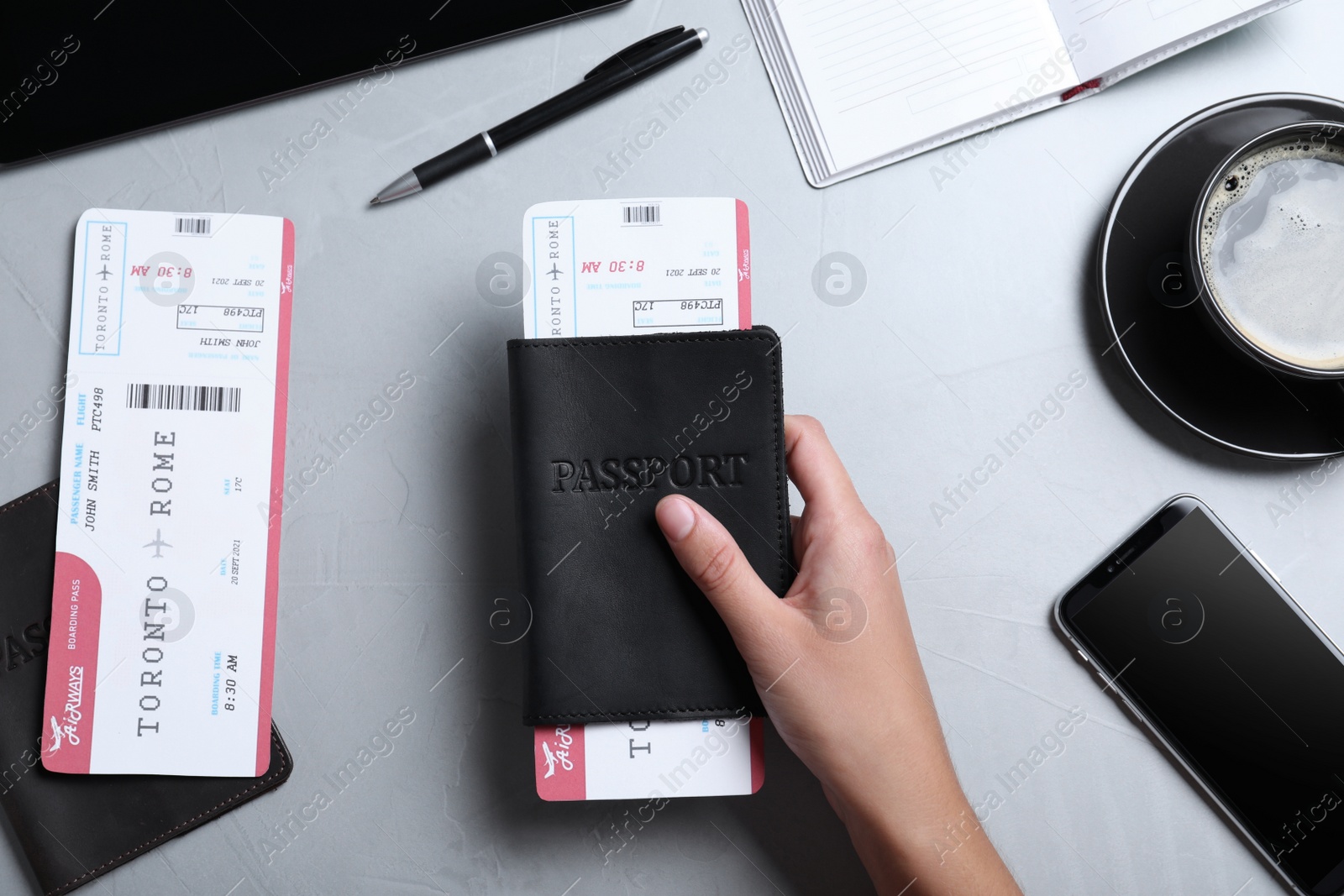 Photo of Woman holding passport and ticket at table, top view. Travel agency concept