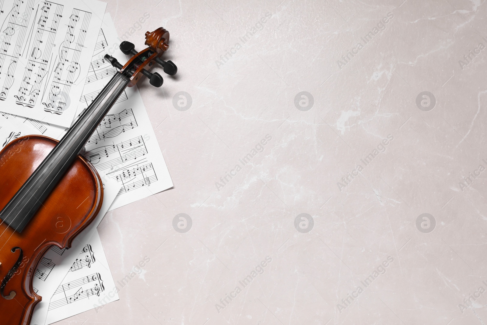 Photo of Violin and music sheets on grey marble table, top view. Space for text