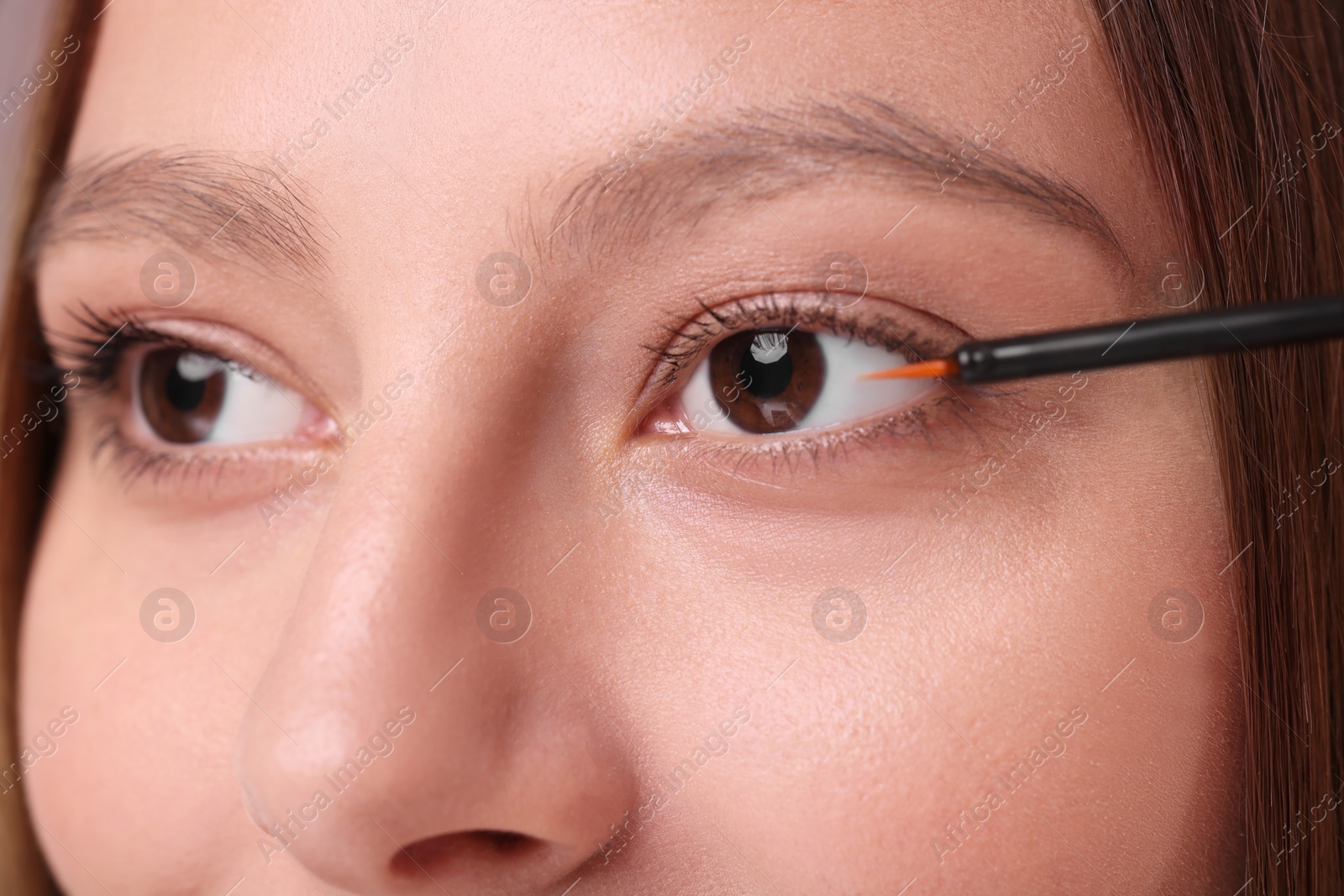 Photo of Woman applying serum onto eyelashes, closeup view