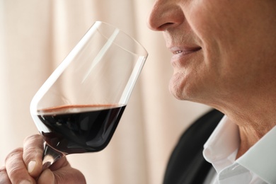 Photo of Senior man with glass of wine indoors, closeup